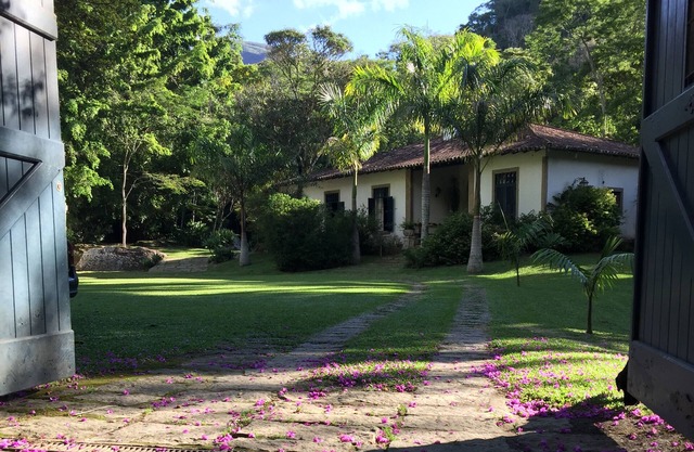 Colonial house with a smaller house on the edge of a river and along the forest.