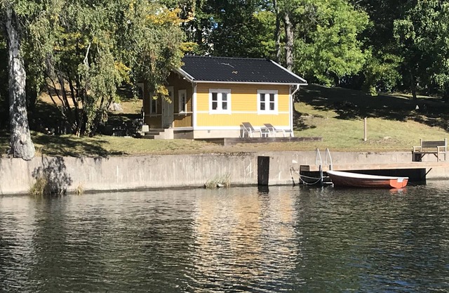 Cottage with sunny wooden deck by water. Rowing boat included.