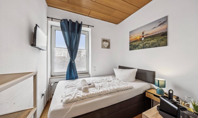 Wilhelmshaven Hotel | Cozy single room, flat-screen TV, and modern bathroom with shower. Ideal for singles and short stays – enjoy a relaxed atmosphere with warm wood accents and coastal charm.